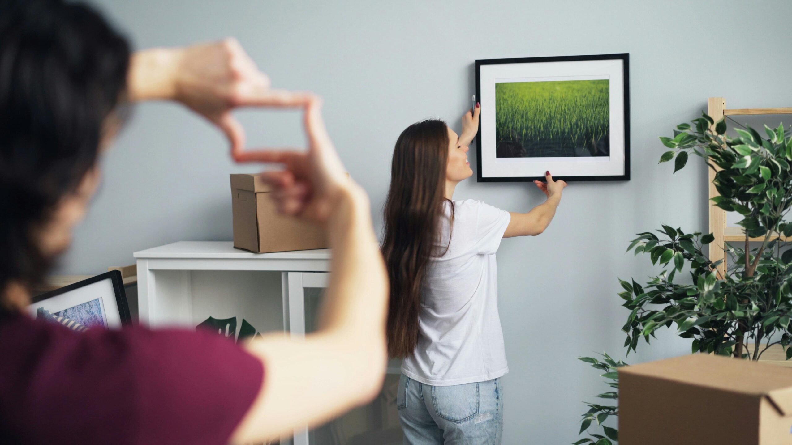 A couple enthusiastically hanging artwork while decorating their new home together.